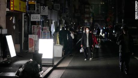 Ludzie chodzą ulicą podczas przerwy w dostawie prądu w Tokio.
