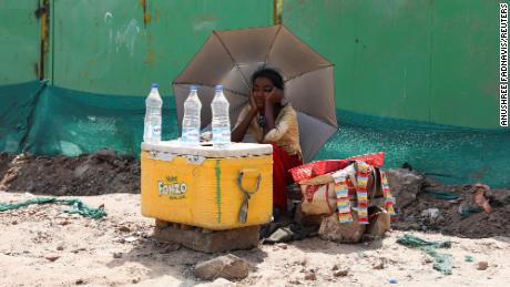 Dziewczyna sprzedająca wodę używa parasola, by chronić się przed słońcem podczas fali upałów w New Delhi w Indiach.