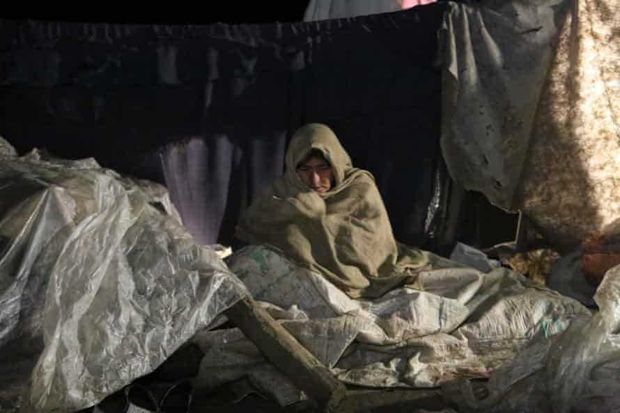 Kobieta w stanie Paktika, która po trzęsieniu ziemi została bezdomna, próbuje się ogrzać.