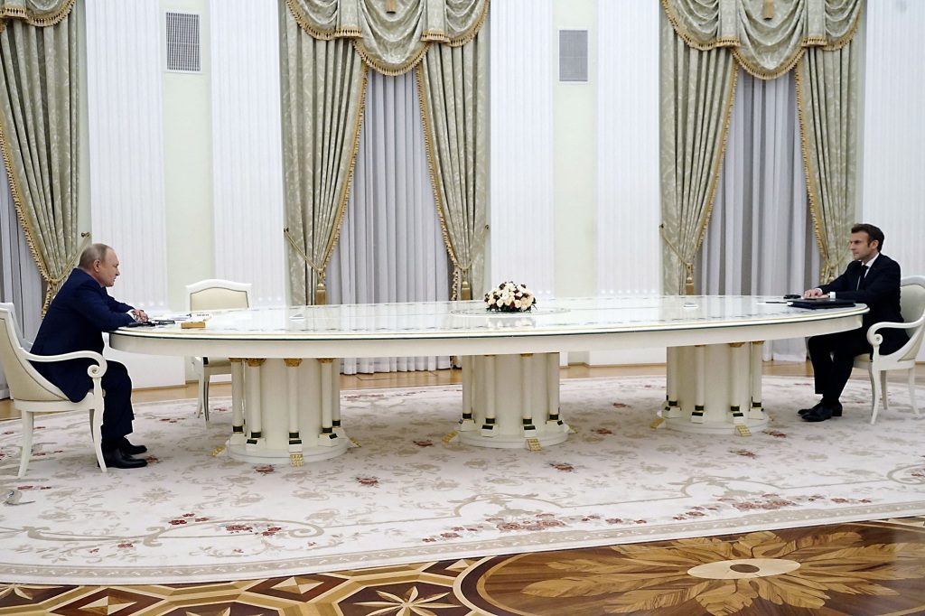Putin i Marcon siedzą naprzeciwko siebie przy stole w Moskwie