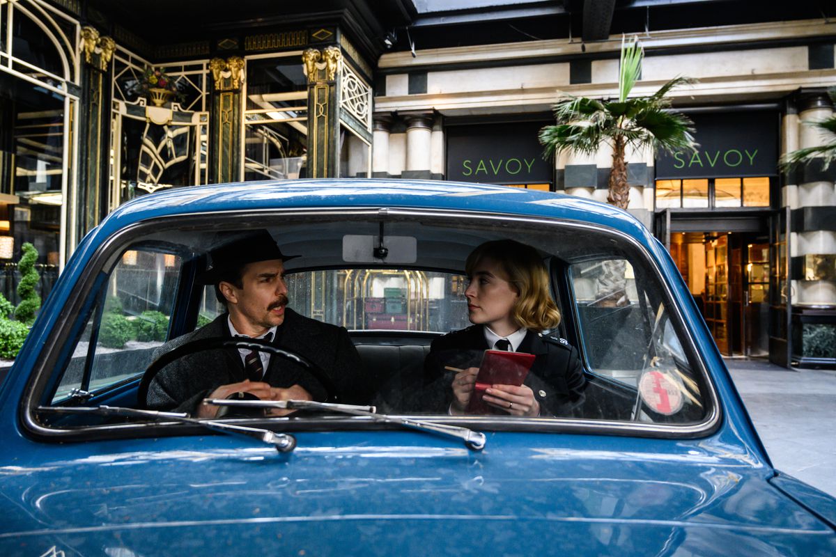 Inspektor Stoppard (Sam Rockwell) i Constable Stalker (Saoirse Ronan) rozmawiają w małym niebieskim samochodzie policyjnym przed hotelem Savoy