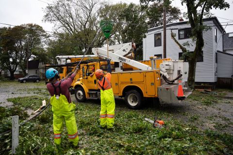 Pracownicy podnoszą powalone druty, aby maszyny mogły dotrzeć do powalonych drzew w Halifax w sobotę.